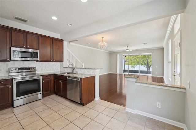 10124 Westpark Preserve Blvd, Tampa, FL 33625 - kitchen featuring appliances with stainless steel finishes, a peninsula, a sink, ornamental molding, and tasteful backsplash