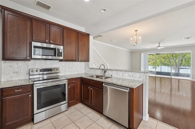 10124 Westpark Preserve Blvd, Tampa, FL 33625 - kitchen with stainless steel appliances, a sink, a chandelier, a peninsula, and tasteful backsplash