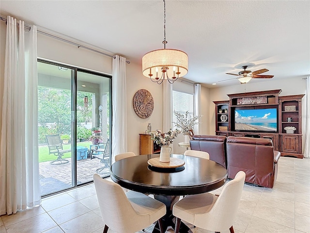 dining area featuring light tile patterned floors, a ceiling fan, and a chandelier