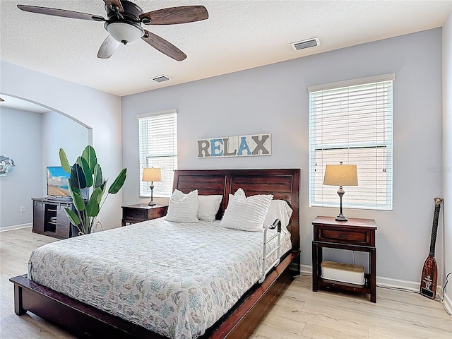 bedroom with light wood-style flooring, baseboards, ceiling fan, and a textured ceiling