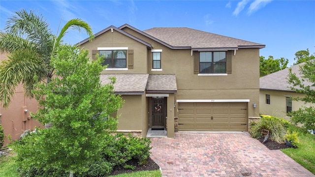 view of front of home featuring stucco siding, a garage, decorative driveway, and a shingled roof
