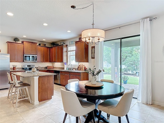 kitchen with appliances with stainless steel finishes, a center island, a chandelier, recessed lighting, and brown cabinets