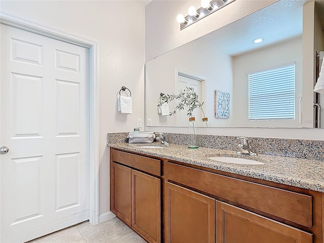 full bathroom featuring double vanity, tile patterned flooring, and baseboards