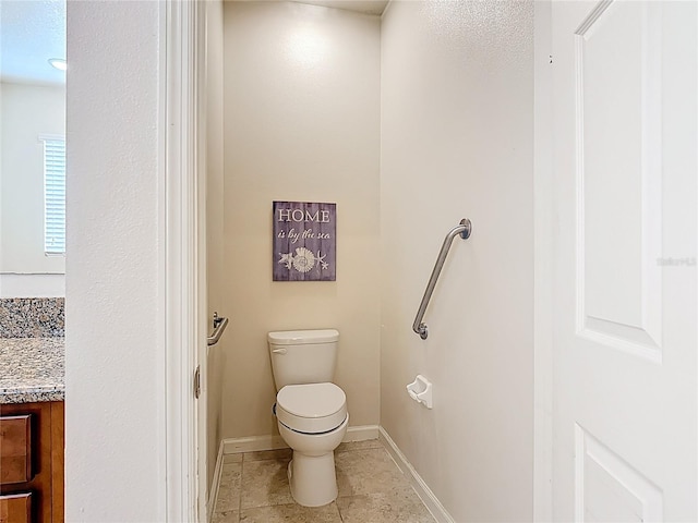 bathroom featuring toilet, vanity, and baseboards