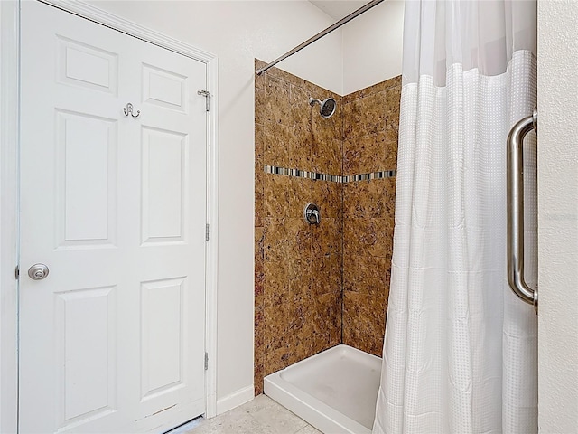 bathroom featuring tiled shower and baseboards