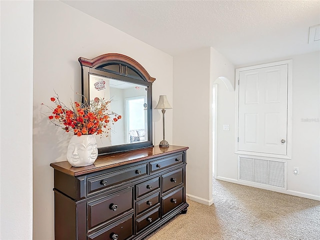 corridor with light carpet, baseboards, arched walkways, and a textured ceiling