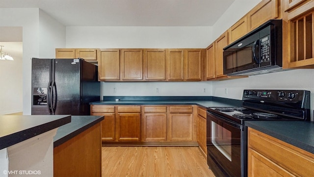 579 Setting Sun Dr, Winter Garden, FL 34787 - kitchen with black appliances, dark countertops, light wood finished floors, and brown cabinets