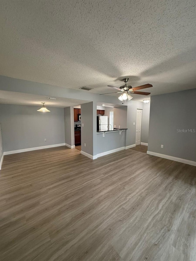 190 Riverbend Dr Unit 102, Altamonte Springs, FL 32714 - unfurnished living room with a textured ceiling, ceiling fan, dark wood-type flooring, and baseboards