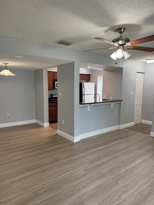 190 Riverbend Dr Unit 102, Altamonte Springs, FL 32714 - unfurnished living room featuring wood finished floors, a textured ceiling, ceiling fan, and baseboards