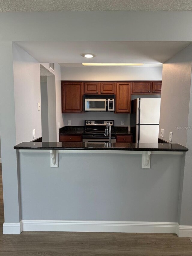190 Riverbend Dr Unit 102, Altamonte Springs, FL 32714 - kitchen featuring freestanding refrigerator, electric range, wood finished floors, and a peninsula
