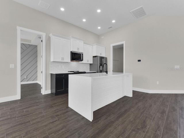 9257 King Hill St, Port Charlotte, FL 33981 - kitchen featuring appliances with stainless steel finishes, dark wood finished floors, a center island with sink, light countertops, and white cabinetry