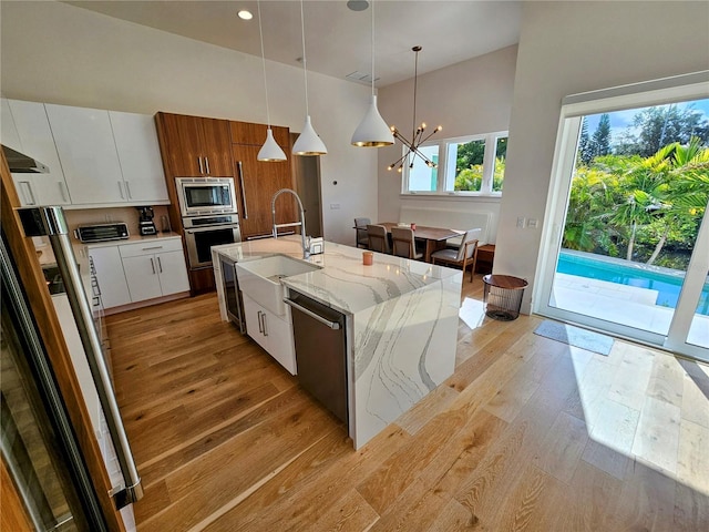 2408 Nassau St, Sarasota, FL 34231 - kitchen featuring stainless steel appliances, light wood-style floors, high vaulted ceiling, white cabinetry, and a chandelier