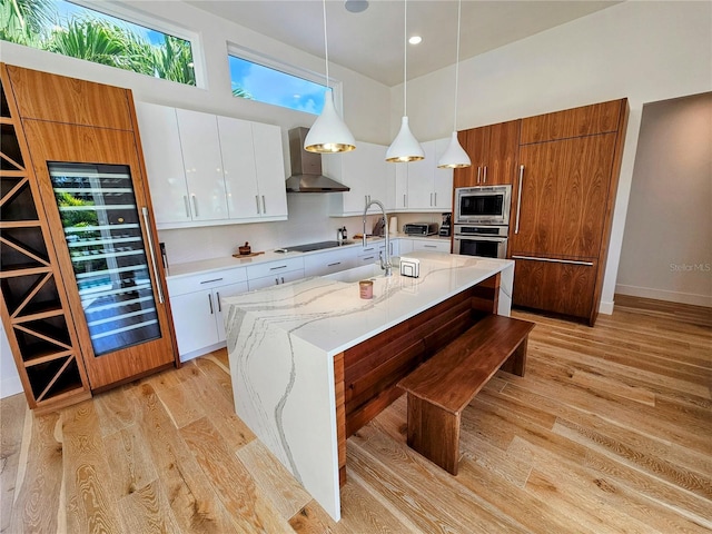 2408 Nassau St, Sarasota, FL 34231 - kitchen with appliances with stainless steel finishes, wall chimney exhaust hood, light wood-type flooring, a center island with sink, and recessed lighting