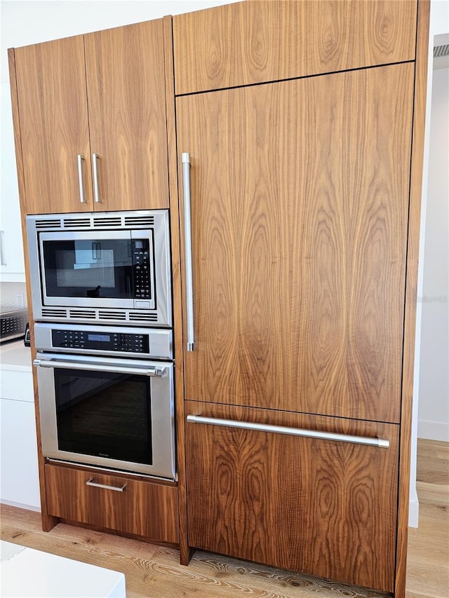 2408 Nassau St, Sarasota, FL 34231 - kitchen with stainless steel appliances, modern cabinets, light wood-style floors, and brown cabinets
