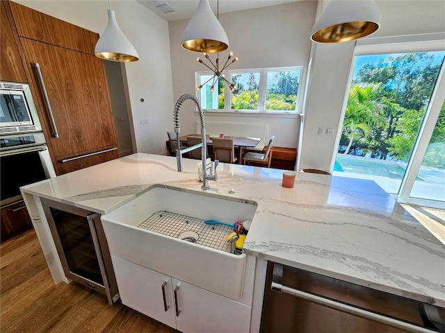 2408 Nassau St, Sarasota, FL 34231 - kitchen featuring appliances with stainless steel finishes, wood finished floors, brown cabinets, wine cooler, and a sink