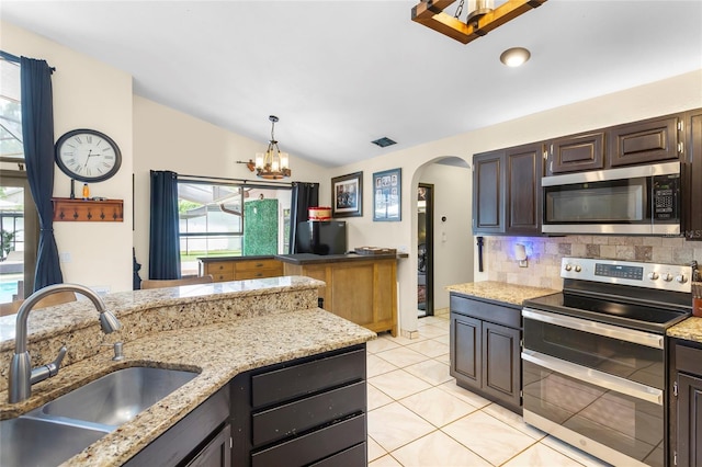 9774 Bohart Ct, Orlando, FL 32836 - kitchen featuring appliances with stainless steel finishes, vaulted ceiling, arched walkways, healthy amount of natural light, and tasteful backsplash
