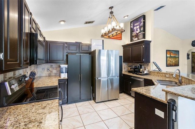9774 Bohart Ct, Orlando, FL 32836 - kitchen with stainless steel appliances, vaulted ceiling, backsplash, light stone counters, and decorative light fixtures