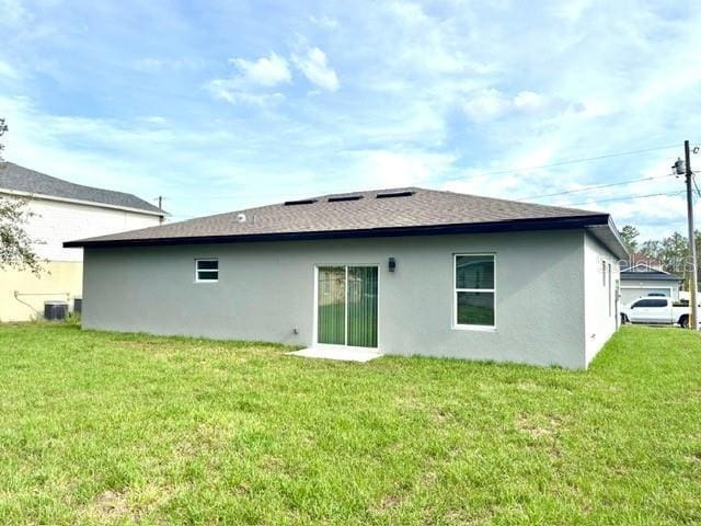 319 Anchovie Ct, Poinciana, FL 34759 - back of house with stucco siding, a yard, and a shingled roof