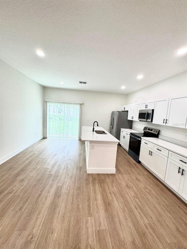 319 Anchovie Ct, Poinciana, FL 34759 - kitchen with appliances with stainless steel finishes, a sink, light wood finished floors, white cabinets, and a textured ceiling