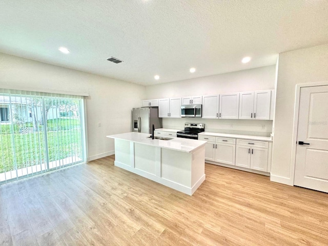 319 Anchovie Ct, Poinciana, FL 34759 - kitchen featuring stainless steel appliances, a sink, light wood-style flooring, light countertops, and a kitchen island with sink