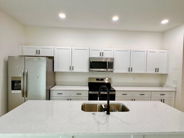 319 Anchovie Ct, Poinciana, FL 34759 - kitchen featuring stainless steel appliances, a sink, a center island with sink, recessed lighting, and light stone countertops