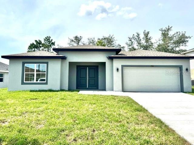 319 Anchovie Ct, Poinciana, FL 34759 - view of front facade with a garage, driveway, a front lawn, and stucco siding
