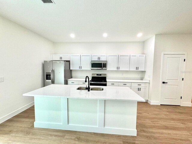 319 Anchovie Ct, Poinciana, FL 34759 - kitchen with appliances with stainless steel finishes, a sink, white cabinetry, a center island with sink, and baseboards