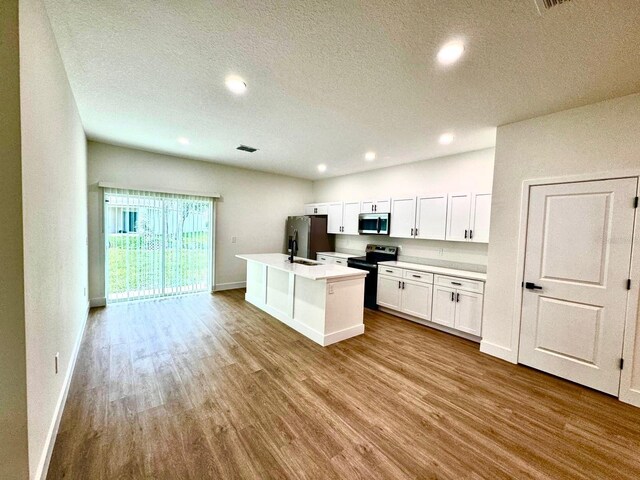 319 Anchovie Ct, Poinciana, FL 34759 - kitchen featuring appliances with stainless steel finishes, baseboards, wood finished floors, white cabinetry, and a textured ceiling