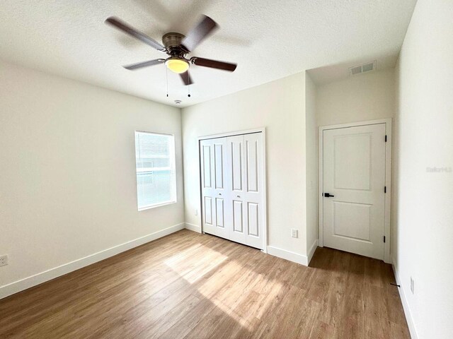 319 Anchovie Ct, Poinciana, FL 34759 - unfurnished bedroom with wood finished floors, a closet, baseboards, a ceiling fan, and a textured ceiling