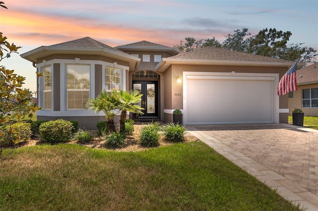 9426 Burnam Dr, Weeki Wachee, FL 34613 - view of front of house with stucco siding, an attached garage, a lawn, and decorative driveway