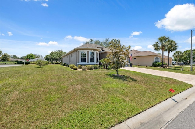 9426 Burnam Dr, Weeki Wachee, FL 34613 - view of front facade featuring concrete driveway, a front lawn, and stucco siding