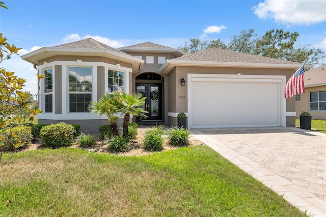 9426 Burnam Dr, Weeki Wachee, FL 34613 - view of front of property featuring stucco siding, a garage, a front lawn, and decorative driveway