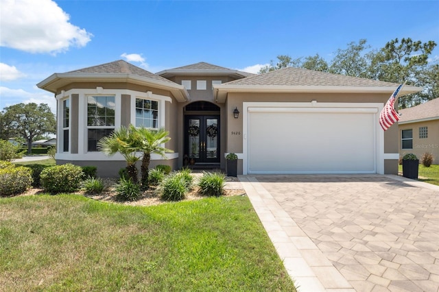 9426 Burnam Dr, Weeki Wachee, FL 34613 - view of front of property featuring french doors, stucco siding, driveway, an attached garage, and a front lawn
