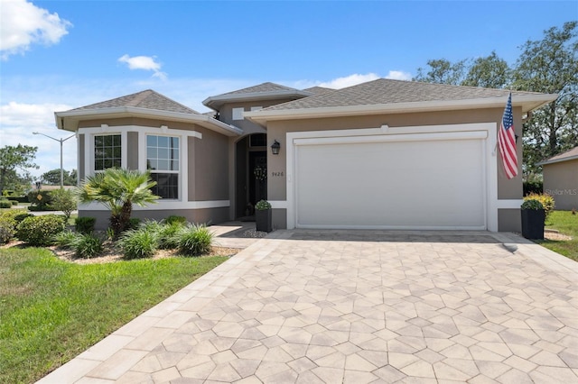 9426 Burnam Dr, Weeki Wachee, FL 34613 - view of front of house featuring decorative driveway, stucco siding, an attached garage, and a front lawn