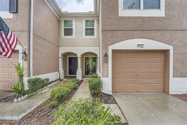 26622 Castleview Way, Wesley Chapel, FL 33544 - doorway to property featuring stucco siding, an attached garage, and concrete driveway