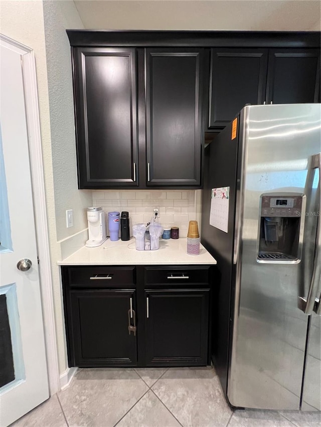 11097 N Folklore St, Winter Garden, FL 34787 - kitchen with stainless steel fridge, dark cabinets, light tile patterned floors, light countertops, and tasteful backsplash