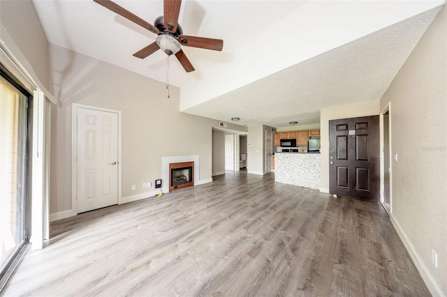 420 Forestway Cir Unit 306, Altamonte Springs, FL 32701 - unfurnished living room with a fireplace, wood finished floors, a ceiling fan, baseboards, and a towering ceiling