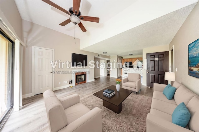 420 Forestway Cir Unit 306, Altamonte Springs, FL 32701 - living room featuring light wood-style floors, ceiling fan, a fireplace, baseboards, and a textured ceiling