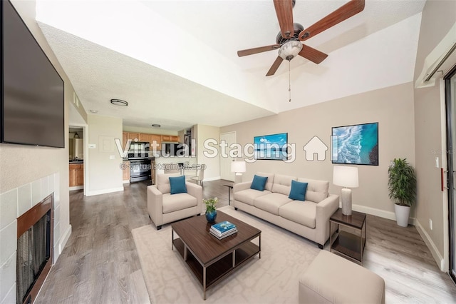 420 Forestway Cir Unit 306, Altamonte Springs, FL 32701 - living area featuring wood finished floors, a ceiling fan, baseboards, a fireplace, and a textured ceiling
