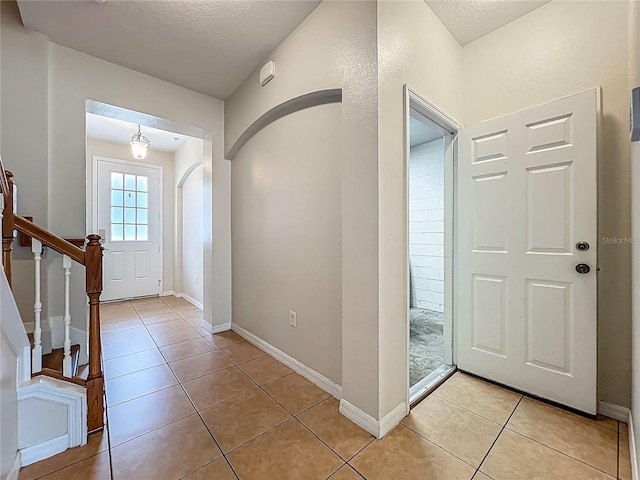 2005 Compass Flower Way, Ocoee, FL 34761 - foyer with light tile patterned floors, stairs, baseboards, arched walkways, and a textured ceiling