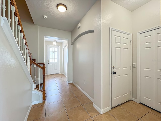 2005 Compass Flower Way, Ocoee, FL 34761 - entryway featuring a textured ceiling, light tile patterned floors, stairway, baseboards, and arched walkways