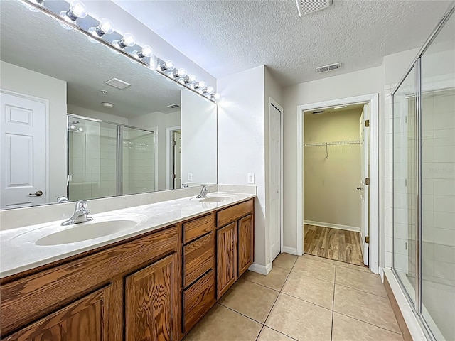 2005 Compass Flower Way, Ocoee, FL 34761 - bathroom with a stall shower, double vanity, a textured ceiling, tile patterned floors, and a spacious closet