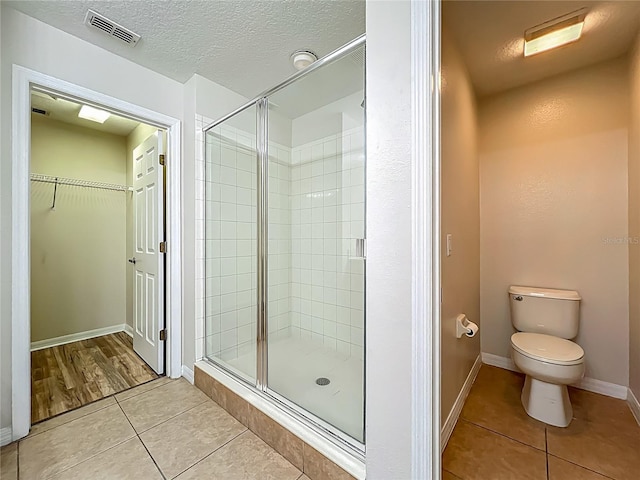 2005 Compass Flower Way, Ocoee, FL 34761 - full bath featuring a shower stall, tile patterned flooring, toilet, a walk in closet, and a textured ceiling