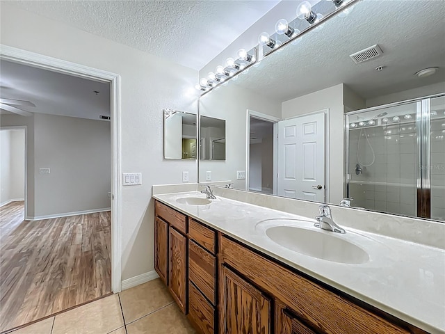 2005 Compass Flower Way, Ocoee, FL 34761 - full bathroom featuring a textured ceiling, double vanity, a stall shower, tile patterned floors, and baseboards