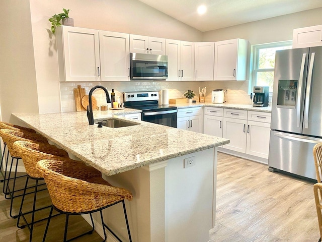 4865 S Tromp Loop, Homosassa, FL 34448 - kitchen featuring appliances with stainless steel finishes, a sink, lofted ceiling, white cabinetry, and light stone counters
