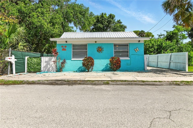 318 Palm St, New Smyrna Beach, FL 32168 - view of front of property with stucco siding, metal roof, and a gate