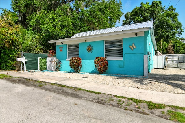 318 Palm St, New Smyrna Beach, FL 32168 - bungalow-style home with stucco siding, a gate, and metal roof