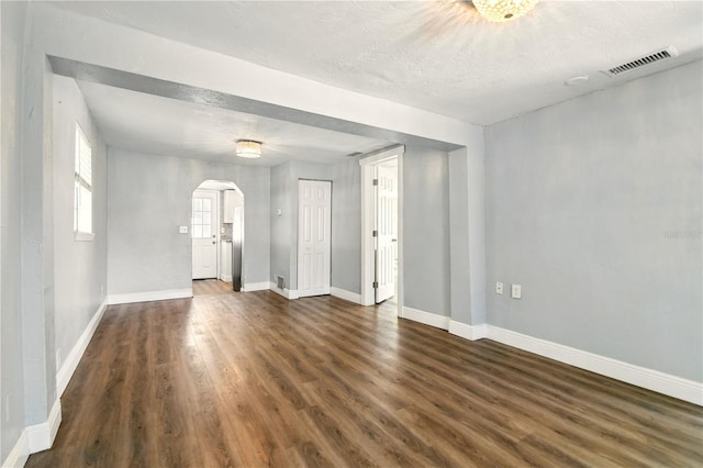 318 Palm St, New Smyrna Beach, FL 32168 - spare room featuring arched walkways, wood finished floors, baseboards, and a textured ceiling