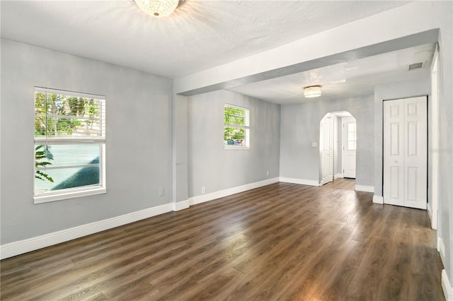 318 Palm St, New Smyrna Beach, FL 32168 - empty room with arched walkways, baseboards, and dark wood-type flooring