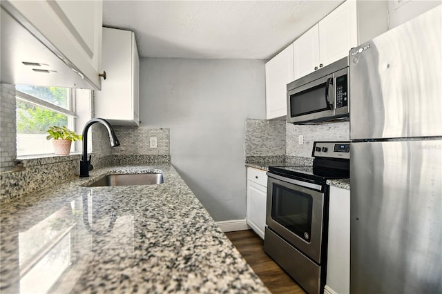 318 Palm St, New Smyrna Beach, FL 32168 - kitchen with appliances with stainless steel finishes, a sink, dark wood-style flooring, tasteful backsplash, and white cabinets